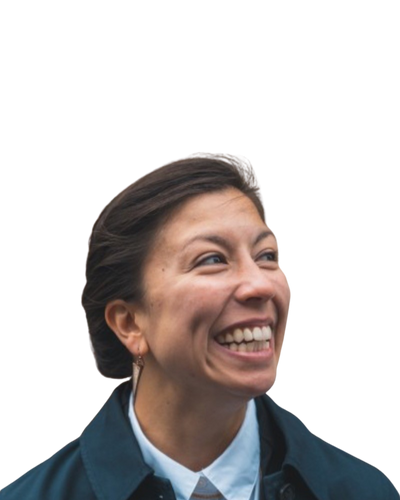 A close up headshot of a person with a fair complexion smiling looking to their side, with dark brown hair. Wearing a white shirt and a blue jacket.